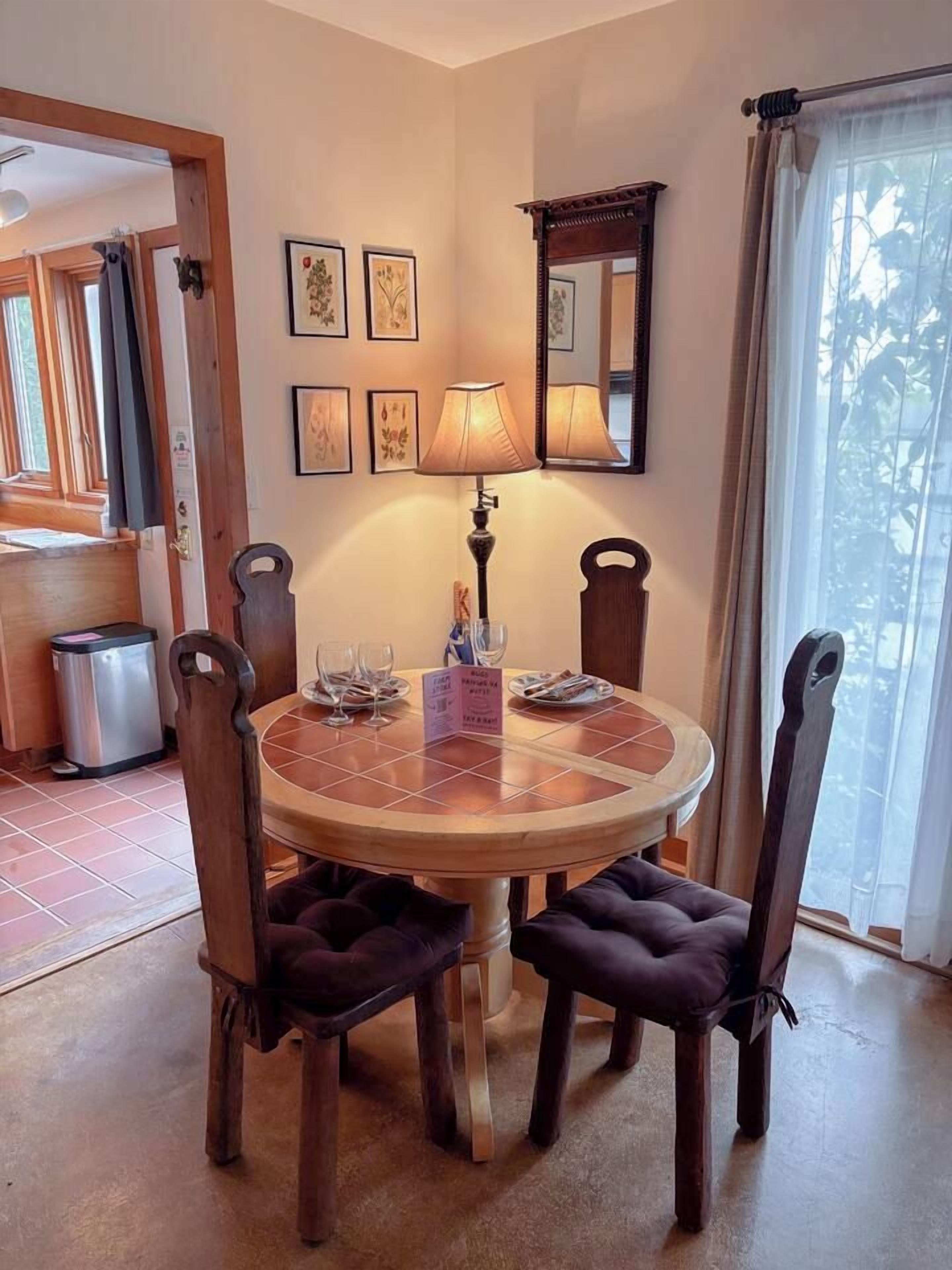 Ein Essbereich mit einem runden Tisch, vier Stühlen, einer Lampe und gerahmten Kunstwerken an der Wand.