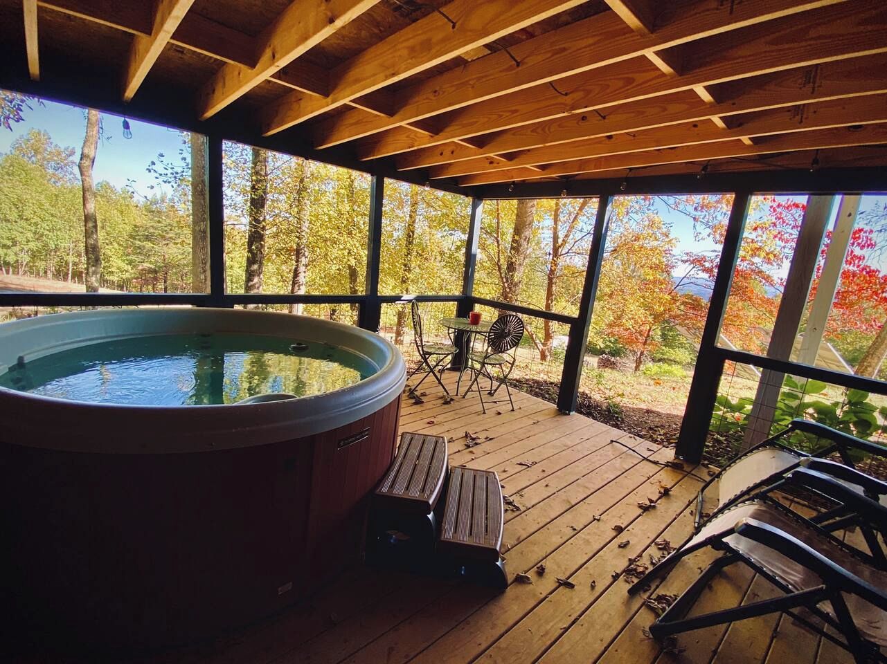 A hot tub on a wooden deck with a view of trees.