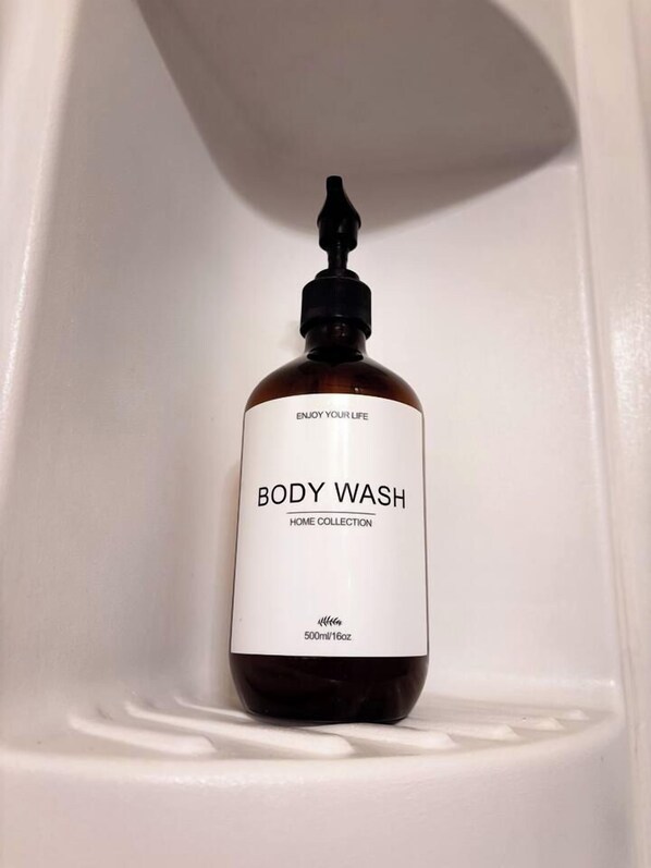 A bottle of body wash in a white bathroom sink.