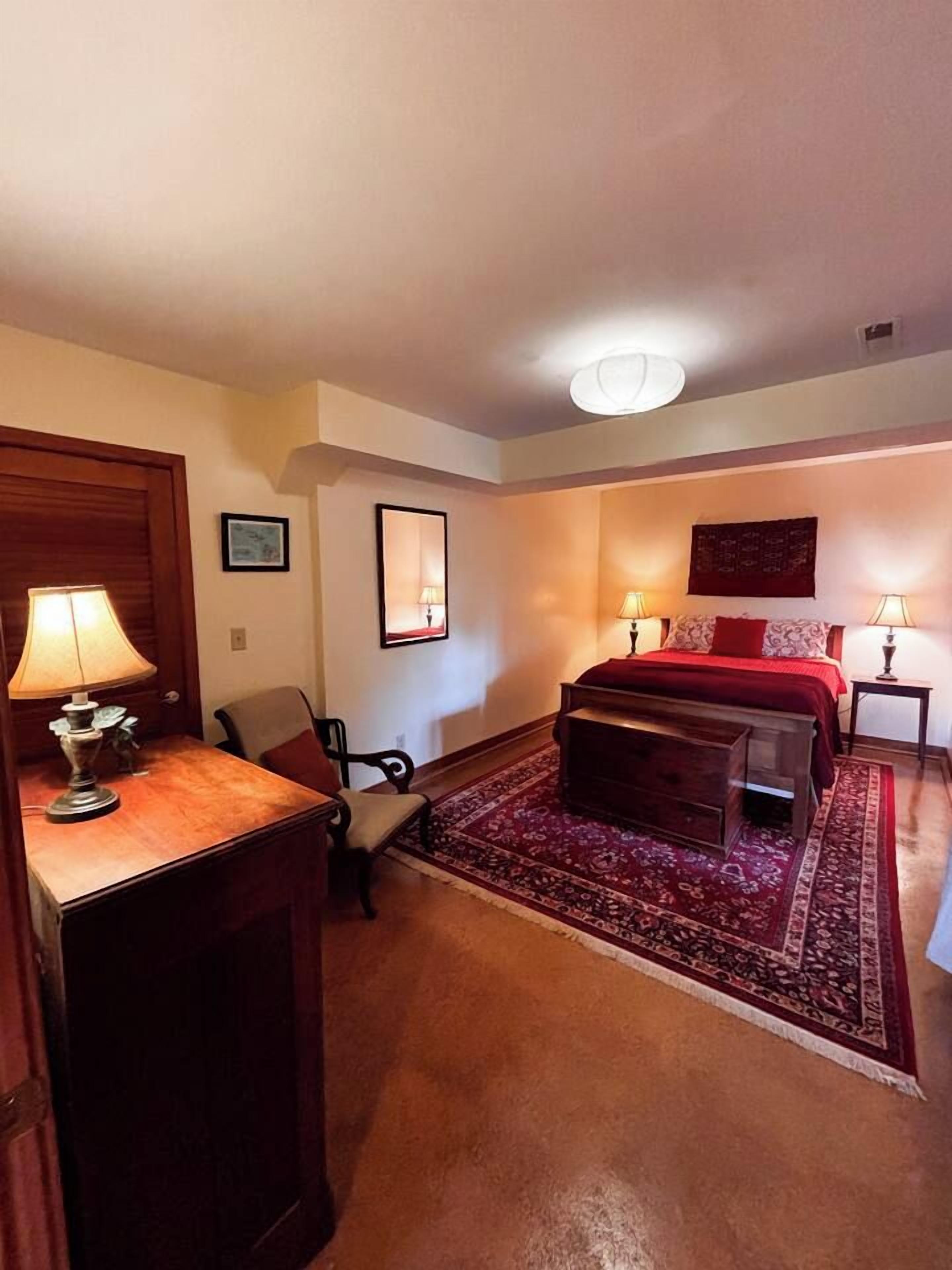 Une chambre à coucher comprenant un lit, un bureau, une chaise et une table de chevet avec des lampes.