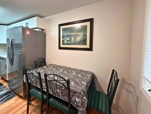 A dining area with a table, chairs, a refrigerator, and a framed picture on the wall. - Freshly Updated Creekside Condo Near Sugar Mountain Resort (Sugar Mountain)