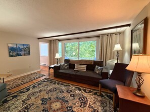 A living room with a sofa, armchairs, a coffee table, a rug, and a painting on the wall. - Freshly Updated Creekside Condo Near Sugar Mountain Resort (Sugar Mountain)