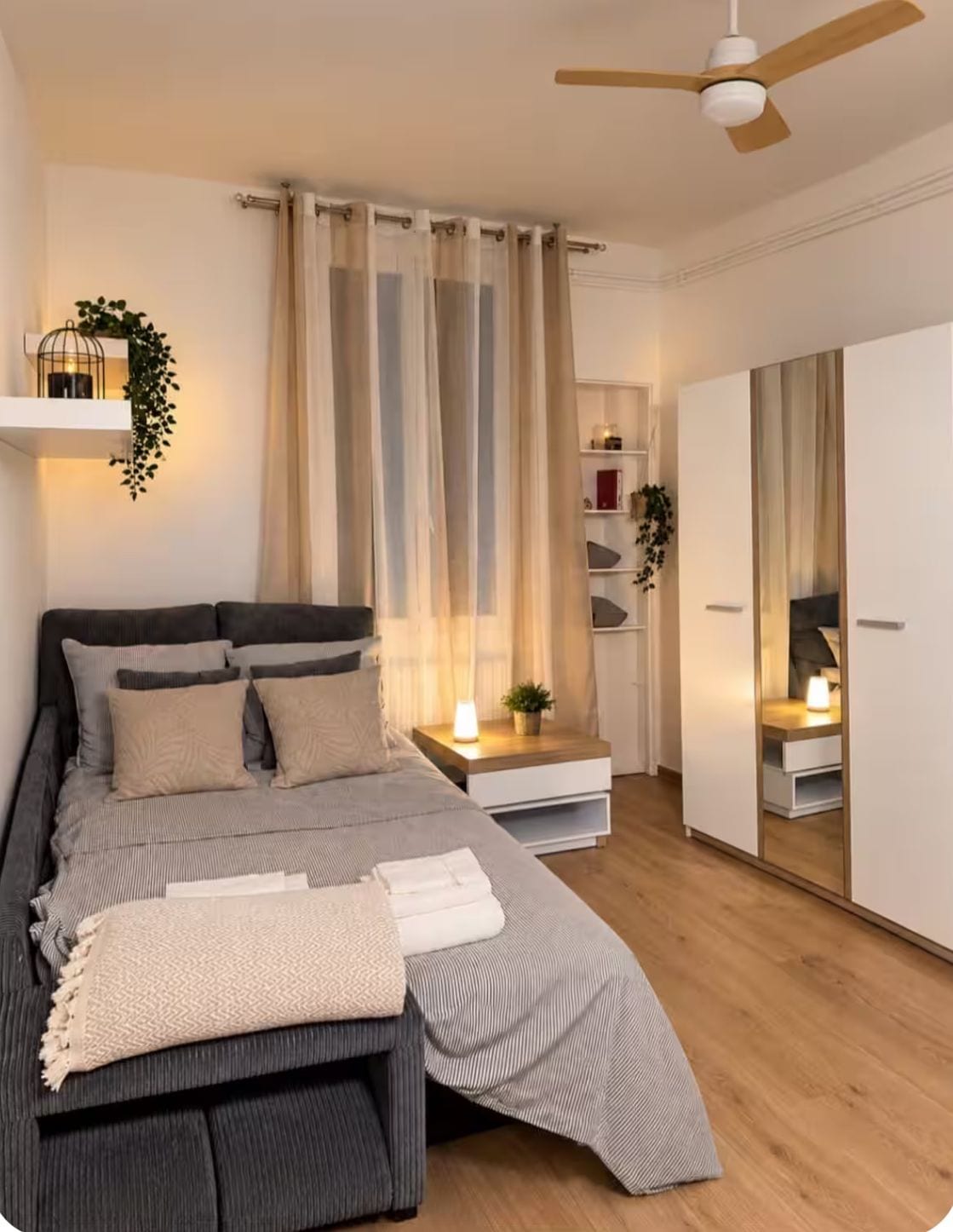 A modern bedroom with a bed, bedside tables, a ceiling fan, and a wardrobe.