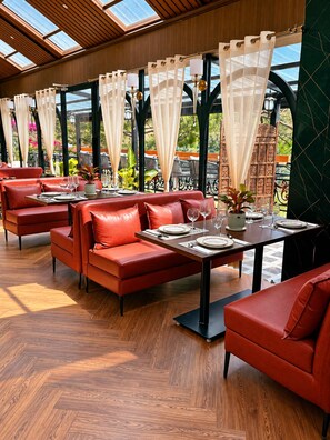 Un restaurant avec des sièges en cuir rouge, des tables en bois et une vue dégagée grâce à de grandes fenêtres.