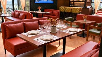Un restaurant avec des sièges en cuir rouge, des tables en bois et un grand écran de télévision diffusant un paysage de montagne.