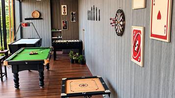 Une pièce équipée de tables de billard, d’un jeu de fléchettes et de jeux de cartes accrochés au mur.