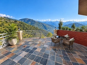 Une terrasse avec vue sur les montagnes, une table avec des chaises et une plante en pot.
