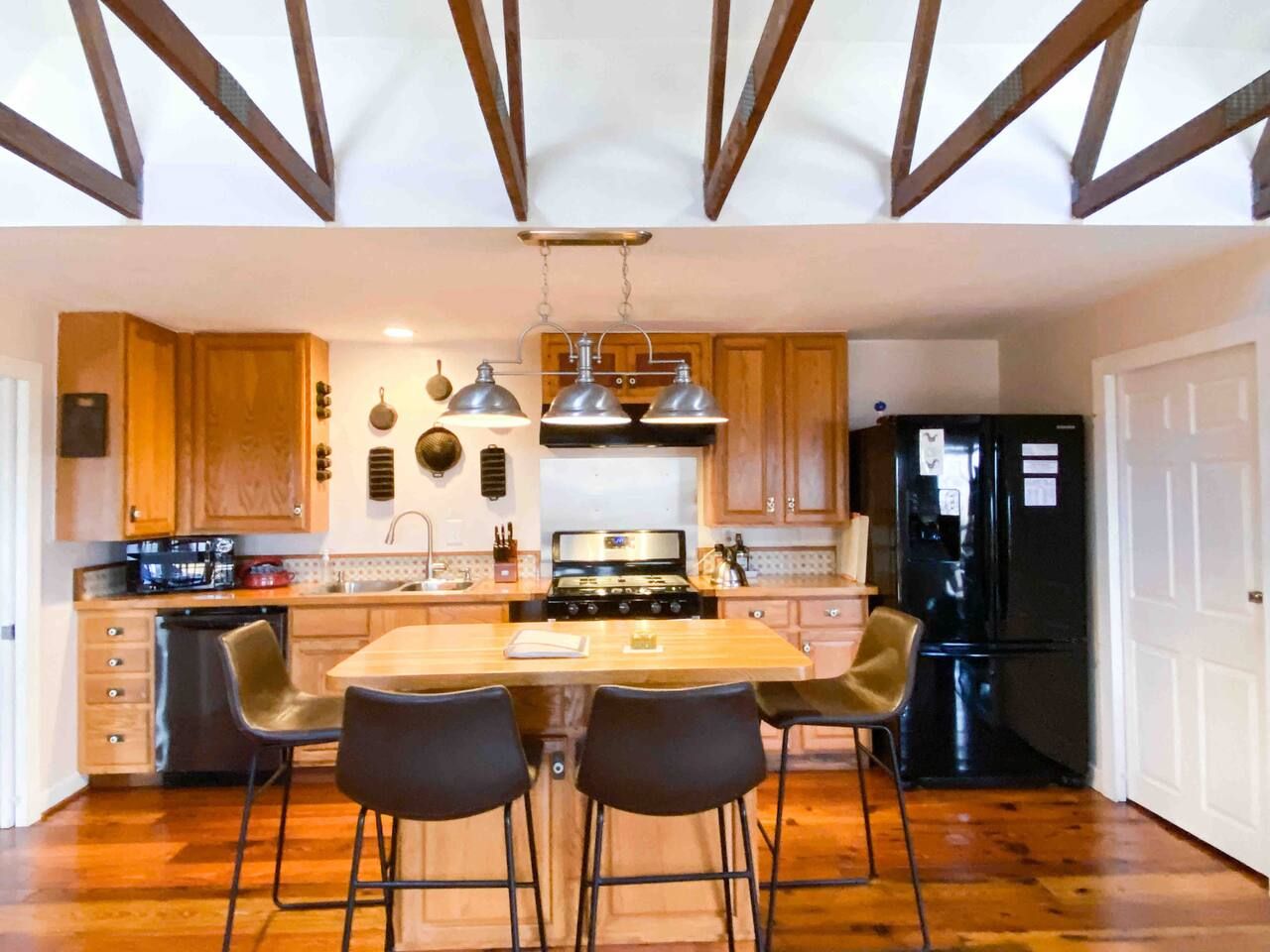 Une cuisine avec des meubles en bois, un îlot central doté de chaises, une cuisinière et un réfrigérateur.