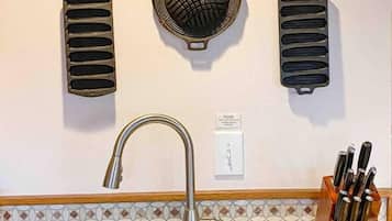 A kitchen with a double sink, a knife block, and wall-mounted cookware.