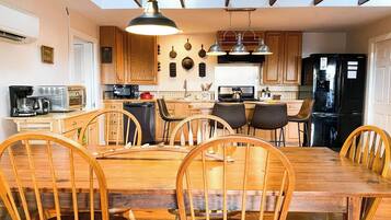 A spacious kitchen with wooden cabinets, a dining table with chairs, and a black refrigerator.
