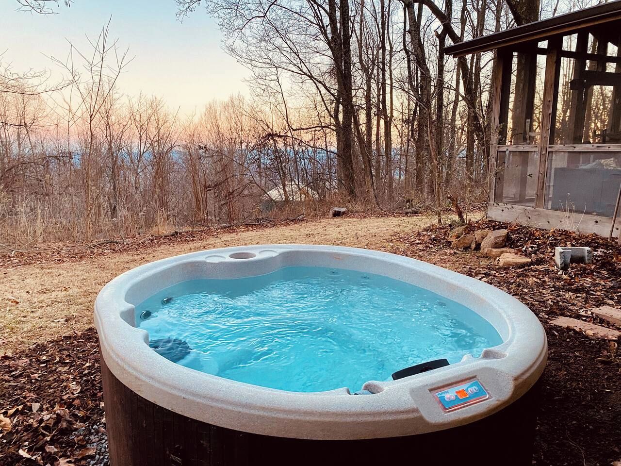 Een hottub in een open omgeving met een houten terras en een grond bedekt met bladeren.