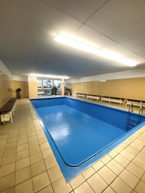 A large indoor swimming pool with a tiled floor and a blue pool edge. - MY STAY - Relaxation by the Lake with a Sauna & Swimming Pool (Prien am Chiemsee)
