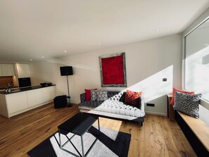 A modern living room with a sofa, a coffee table, and a red accent wall. - MY STAY - Relaxation by the Lake with a Sauna & Swimming Pool (Prien am Chiemsee)