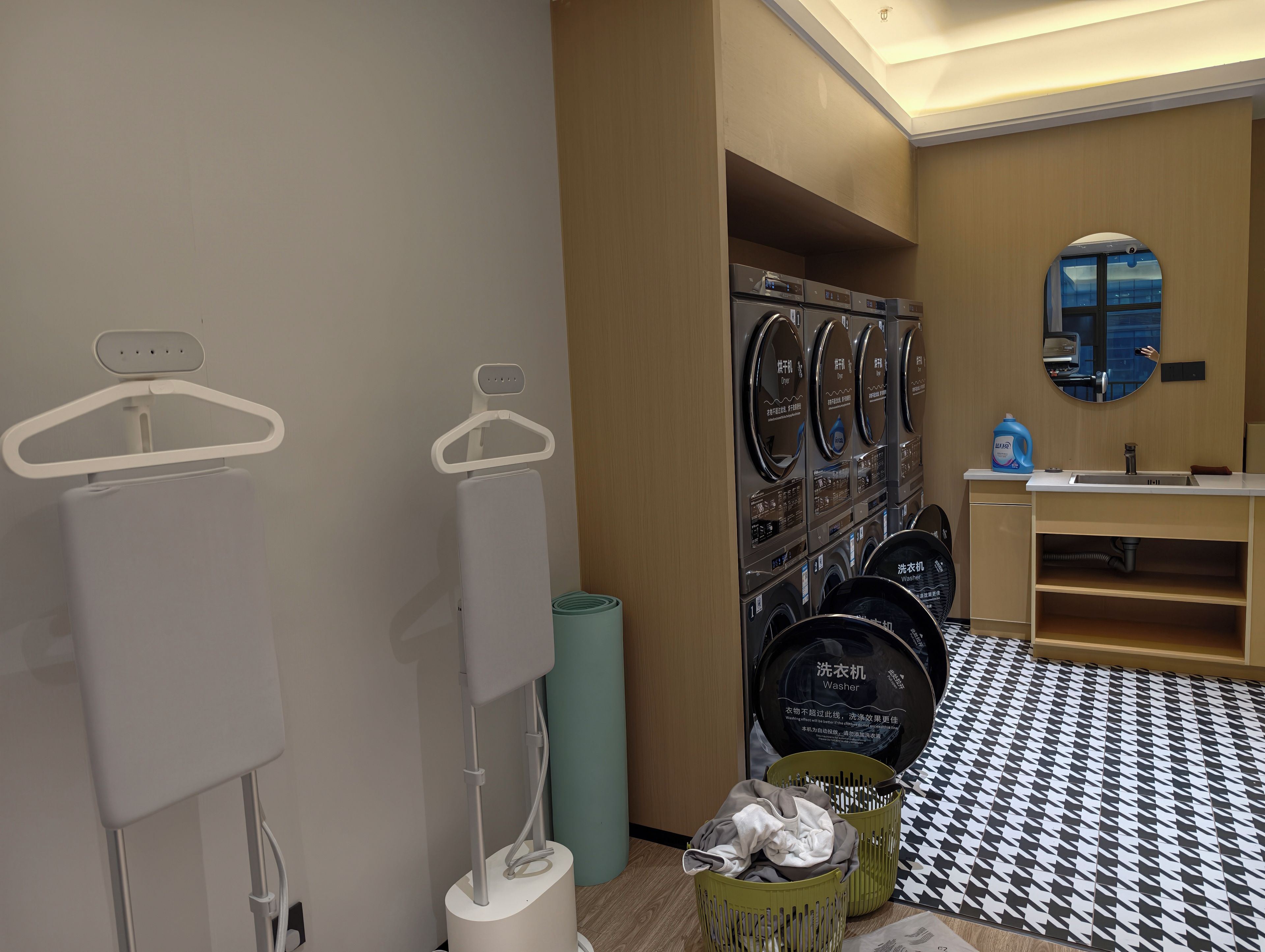 Baño de hotel con lavadora, secadora y lavabo con espejo.