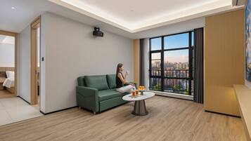 Un soggiorno moderno con un divano verde, un tavolino rotondo e un'ampia finestra con vista sulla città.