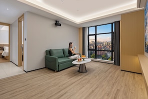 Un saló modern amb un sofà verd, una taula de centre rodona i un finestral gran que ofereix una vista a la ciutat.