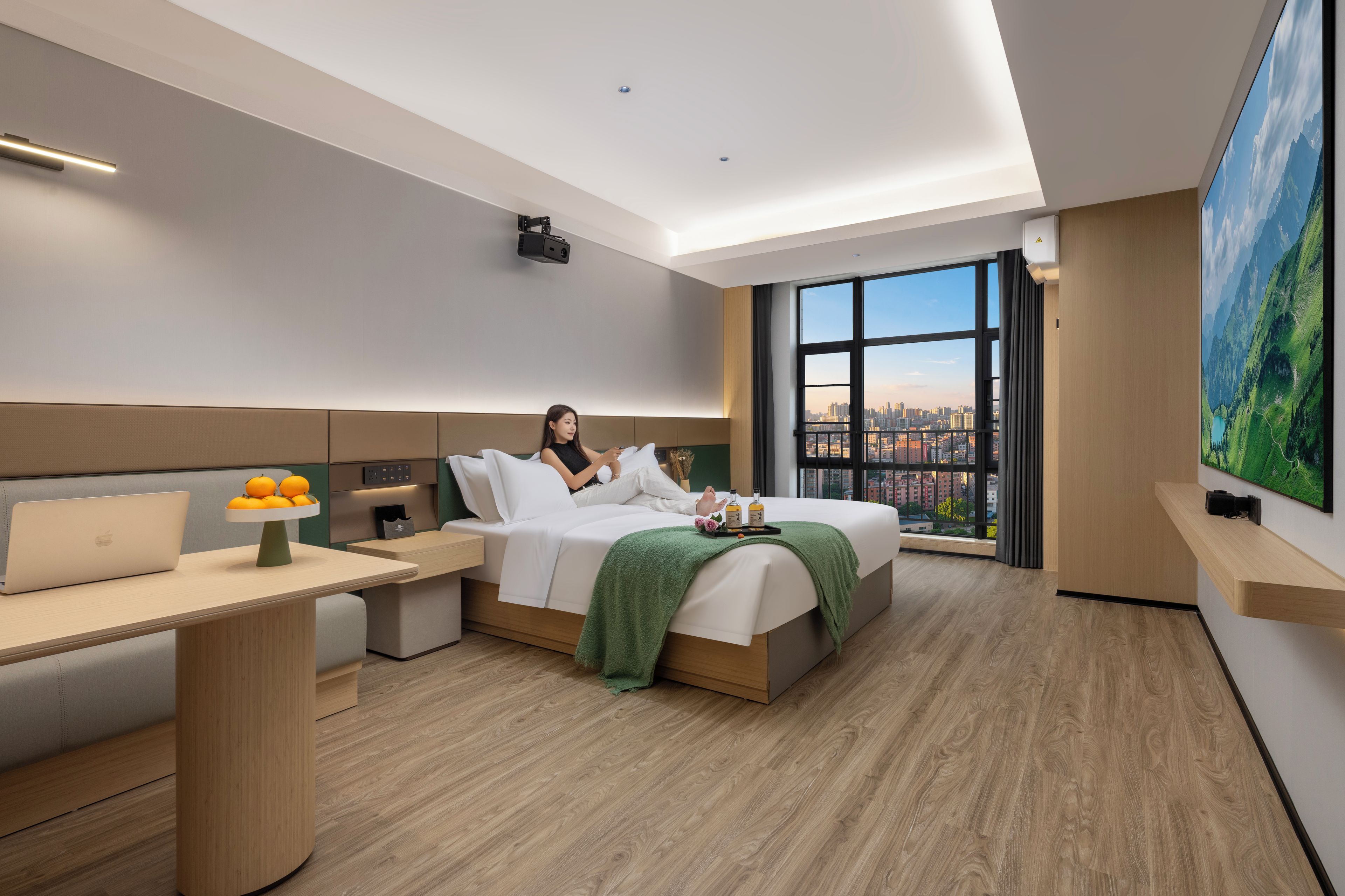 Ein modernes Hotelzimmer mit einem Bett, einem Schreibtisch, einem Stuhl und einem großen Fenster mit Blick auf die Stadt.