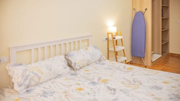Un dormitorio con cama, mesita de noche, lámpara y armario de madera.