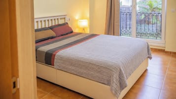 Un dormitorio con una cama, una mesita de noche, una lámpara y vistas al exterior.