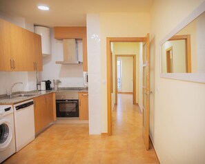 A compact kitchen with a dishwasher, oven, and a washing machine.