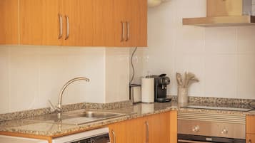 A kitchen with wooden cabinets, a stainless steel sink, a coffee maker, and a dishwasher.