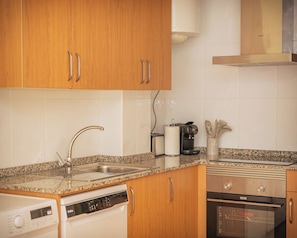 A kitchen with wooden cabinets, a stainless steel sink, a coffee maker, and a dishwasher. - El Rincón da Ría Coastal Getaway by Fomento Beach (O Vicedo)