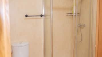 A bathroom with a glass-enclosed shower, a toilet, and a towel rack.