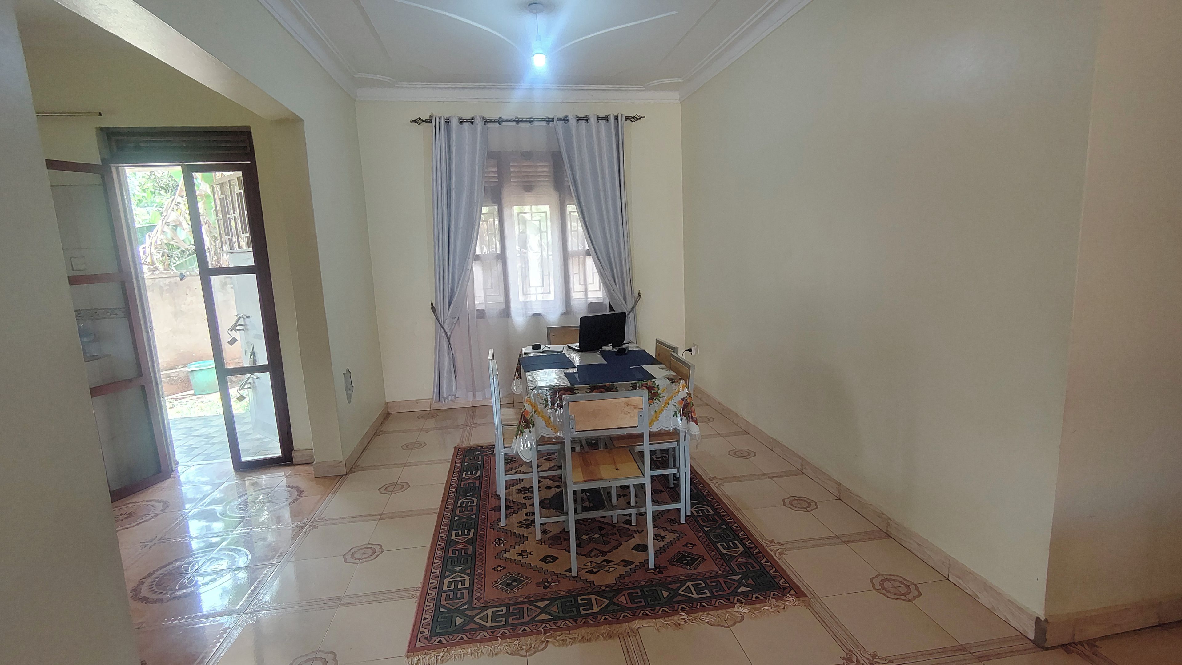 Ein Zimmer mit einem Esstisch, Stühlen, einem Computer und einem gemusterten Teppich.