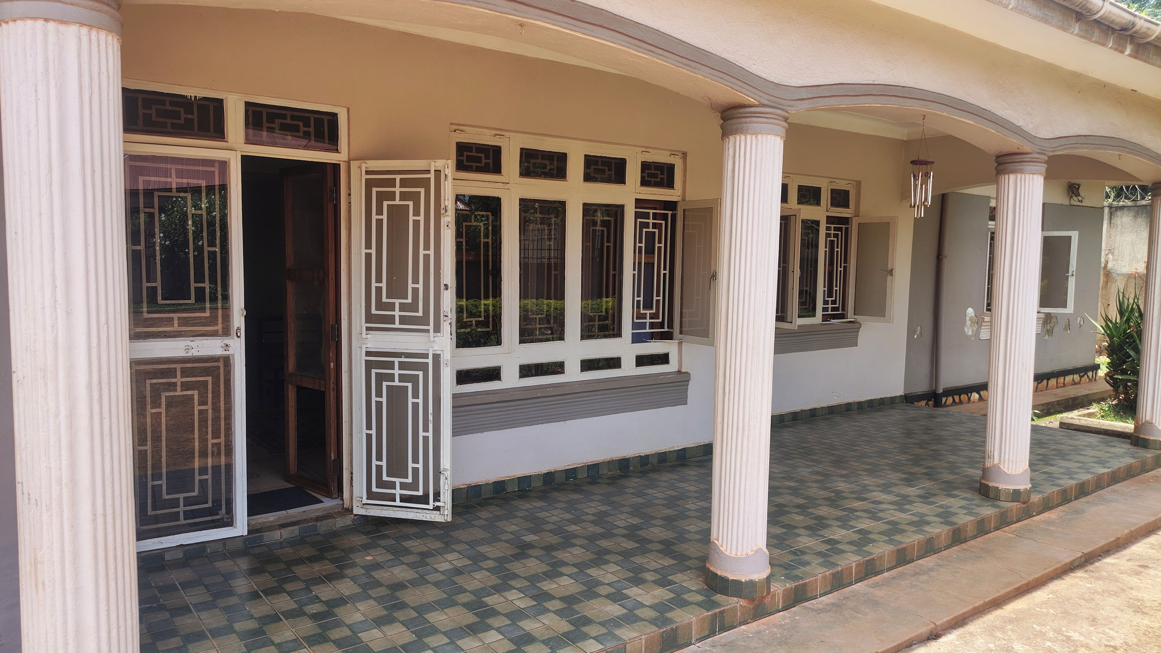 A building with a covered entrance, columns, and a tiled floor.