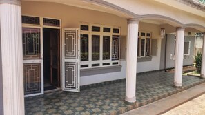 A building with a covered entrance, columns, and a tiled floor.