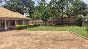 A residential area with a house, a paved driveway, and a grassy yard with trees.