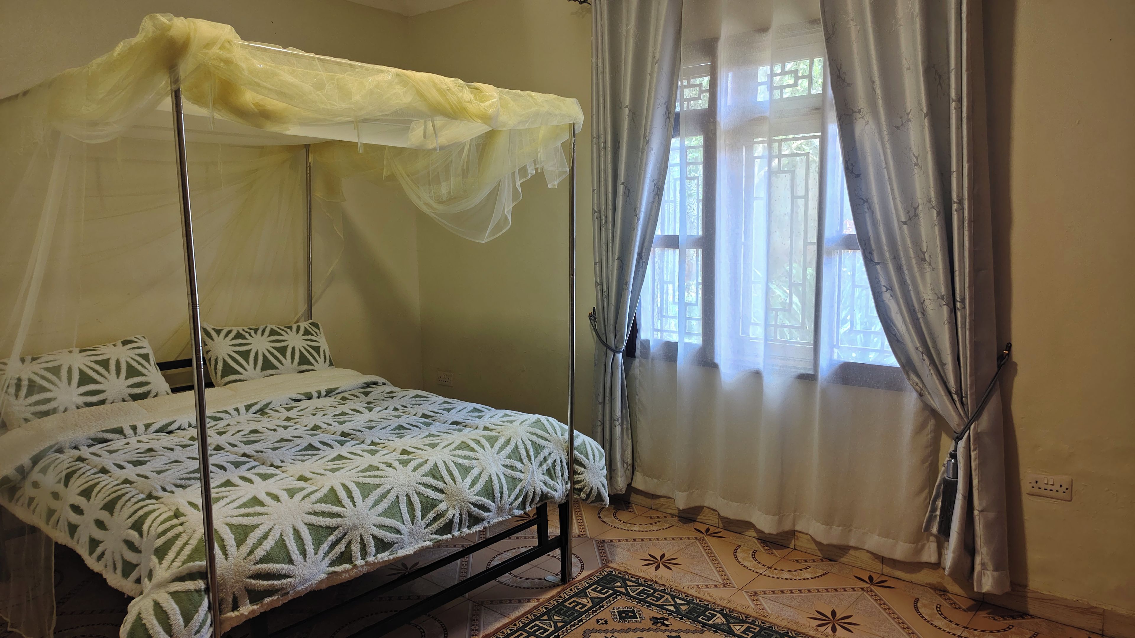 Ein Zimmer mit einem Bett, einem Moskitonetz und Vorhängen mit Muster.