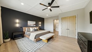 Ein modernes Schlafzimmer mit Bett, Nachttischen, einer Bank, einem Deckenventilator und einem Kleiderschrank.