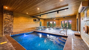 Ein Hallenbad mit Steinwand, Holzboden und Blick ins Freie.