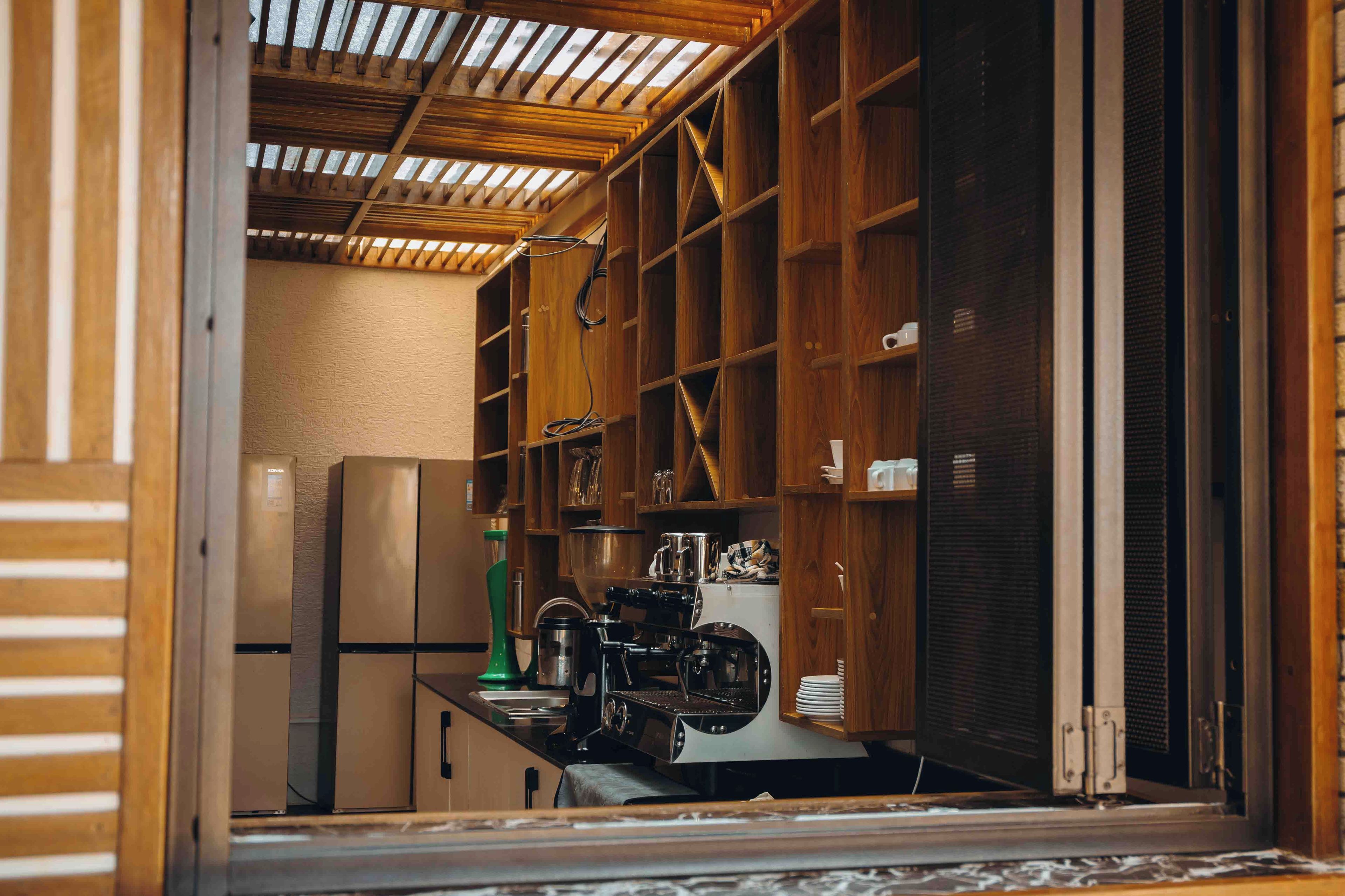 A kitchen with wooden cabinets, a stainless steel refrigerator, and a coffee machine.