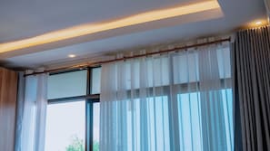 A room with large windows, a wooden ceiling, and a curtain rod. - VELVET SUITES - KIMIRONKO (Kigali)