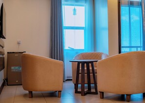 Una sala de estar con dos sillones, una mesita y un ventanal con cortinas.