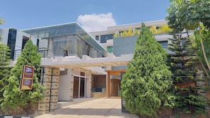 A modern hotel entrance with a glass facade, a brick exterior, and a signboard advertising services. - VELVET SUITES - KIMIRONKO (Kigali)