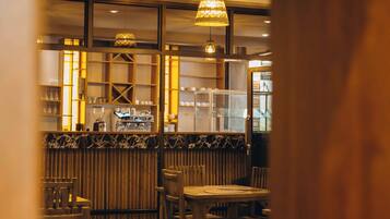 An interior view of a restaurant with wooden furniture, a bar area, and hanging pendant lights.