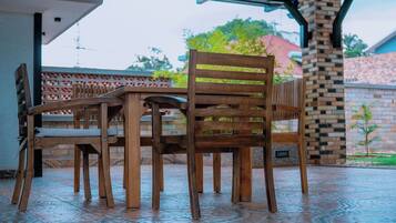 A covered outdoor seating area with wooden furniture and a patterned floor.
