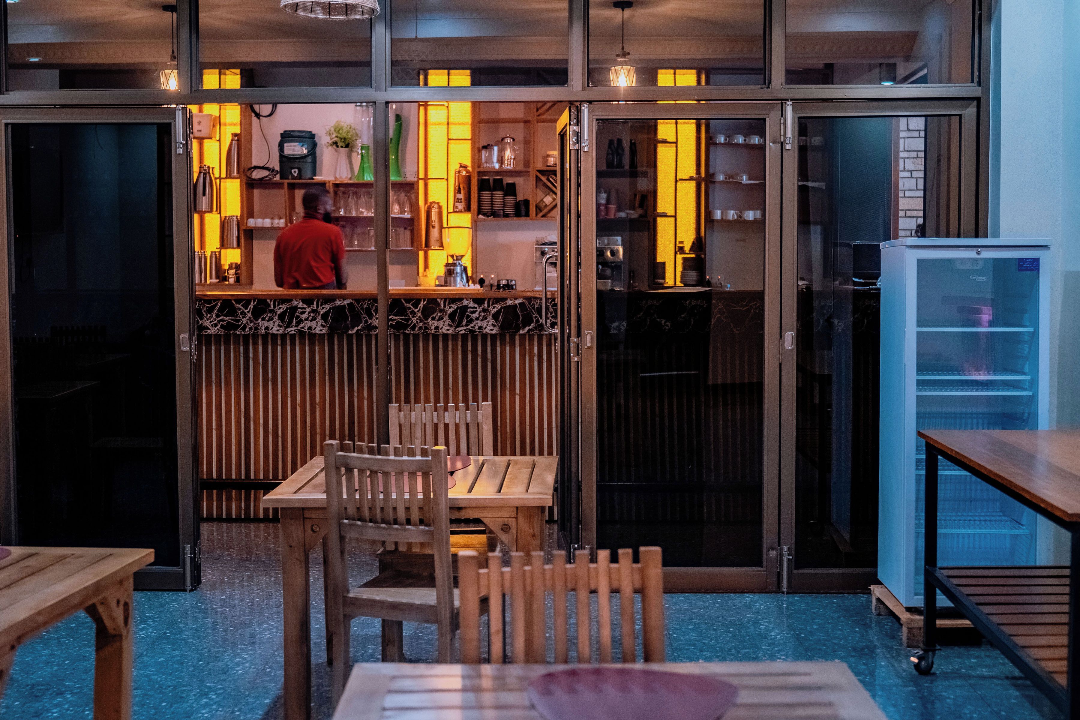 A restaurant interior with a bar area, seating, and a refrigerator.