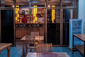 Interior de un restaurante con barra, asientos y un refrigerador.