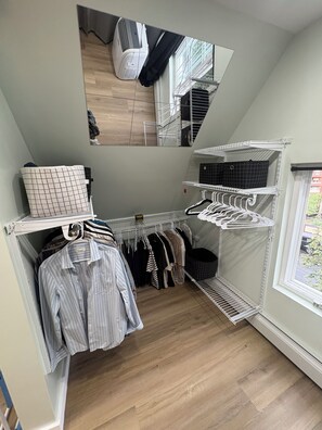 A compact storage room with shelves, a drying rack, and a hanging area for clothes.