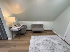 A room with a desk, chair, lamp, and a patterned rug.