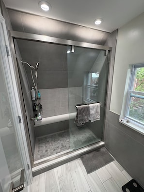 Ein modernes Badezimmer mit einer Duschkabine, einem integrierten Waschbecken und einem Fenster für natürliches Licht.