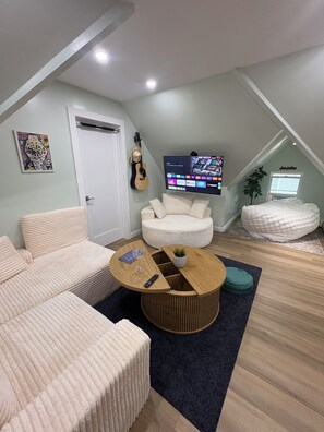Ein modernes Wohnzimmer mit einer Eckcouch, einem runden Couchtisch und einem flachen Fernseher, der an der Wand montiert ist.
