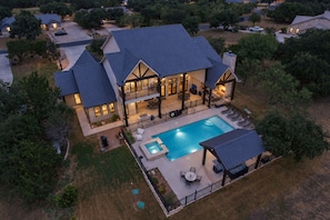 Uma casa de dois andares com piscina, área de estar ao ar livre e um pátio cercado.