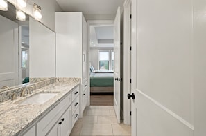 A modern bathroom with a granite countertop, a sink, and a mirror. - Lone Start Lookout@FrioRiverVactionRentals (Concan)