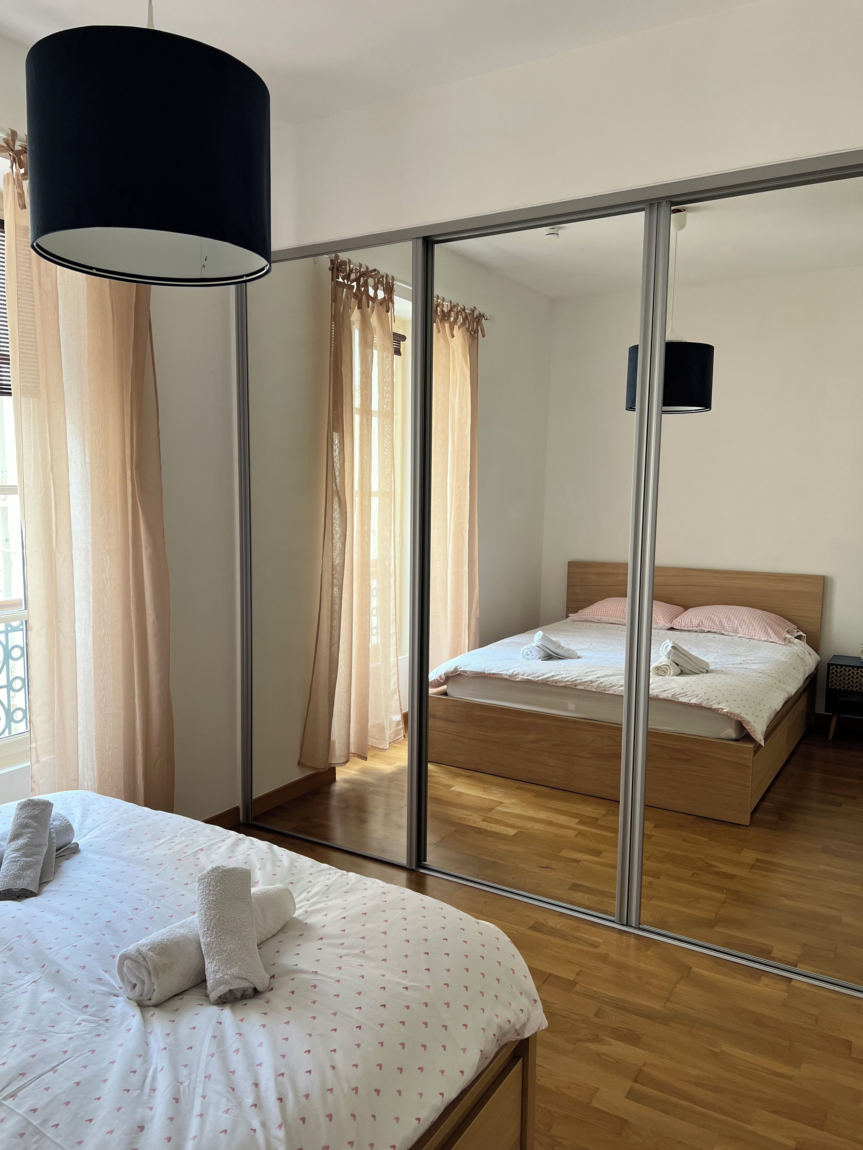 Een slaapkamer met een bed, een spiegel, een kledingkast en een nachtkastje.