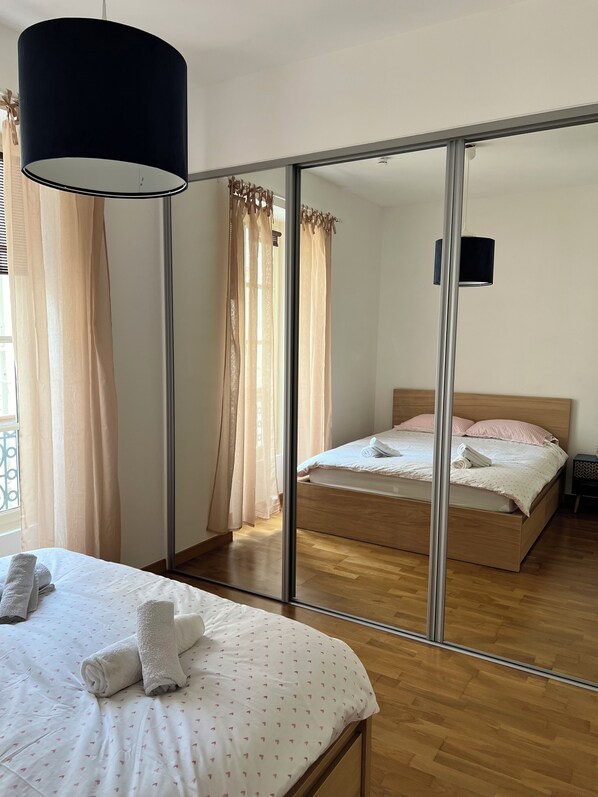 Een slaapkamer met een bed, een spiegel, een kledingkast en een nachtkastje.